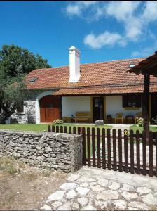 una casa con una valla de madera y una pared de piedra en Casa do Largo en Casais do Chão da Mendiga