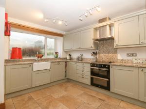 a kitchen with white cabinets and a window at Cwm in Betws-y-coed
