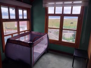 ein Schlafzimmer mit einem Kinderbett in einem Zimmer mit Fenstern in der Unterkunft Horizonte Fueguino II in Ushuaia