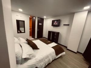 a bedroom with a large bed with a tv on the wall at Hotel Tesla in Bogotá