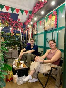 twee mensen zitten in stoelen in een kamer met bloemen bij Old House Homestay in Hanoi