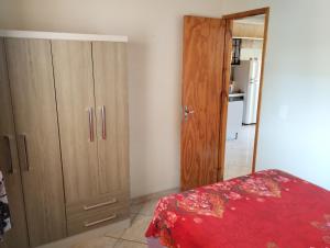 um quarto com um armário de madeira e uma cama vermelha em Lugarzinho Aconchegante - Q1 em Curitiba