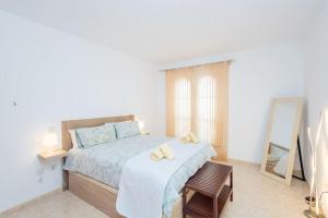 Un dormitorio blanco con una cama y un espejo. en Ático con terraza en Agaete, en Agaete