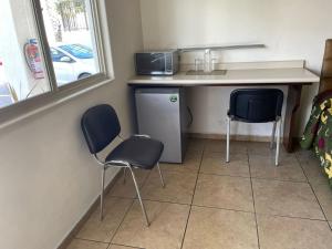 a kitchen with two chairs and a counter and a sink at Hotel las Palmas in Hermosillo