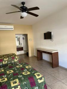 um quarto com uma cama, uma secretária e uma ventoinha de tecto em Hotel las Palmas em Hermosillo