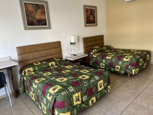 um quarto de hotel com duas camas e uma secretária em Hotel las Palmas em Hermosillo