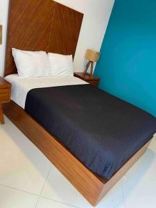 1 dormitorio con 1 cama con cabecero de madera en LA CASA BLANCA Suites Tepic SPA Familiar en Tepic
