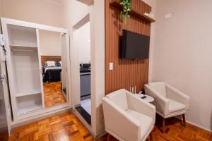 a bathroom with two white chairs and a mirror at Loft Coração da Serra in Serra Negra