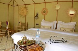 Zimmer mit einem Bett und einem Tablett mit Speisen in der Unterkunft Nomadica Desert Camp in Merzouga