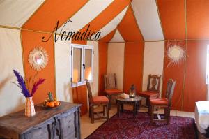 a room with a tent with a table and chairs at Nomadica Desert Camp in Merzouga