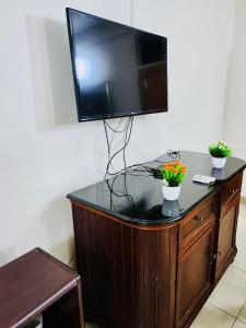 Private Rooms In Osu في آكرا: تلفزيون فوق دولاب خشبي عليه ورد