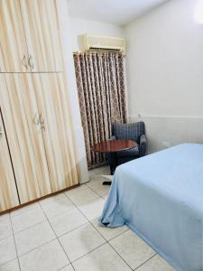 Private Rooms In Osu في آكرا: غرفة نوم بسرير وطاولة وكرسي