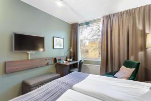 セーデルテリエにあるBest Western Plus Skogshöjdのベッド、テレビ、窓が備わるホテルルームです。