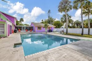 a swimming pool in front of a pink house at Jensen Beach Tropical Resort in Fort Pierce