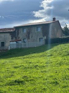 una casa con un campo de hierba delante de ella en RUSTIC HOMES, en San Vicente de la Barquera