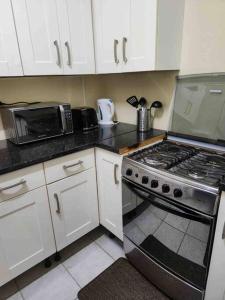 a kitchen with white cabinets and a stove top oven at Browne’s Oceanview Apartments in Arnos Vale