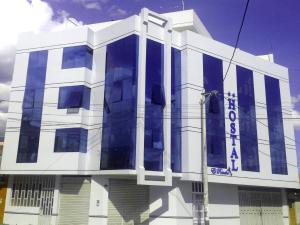 un edificio blanco con ventanas azules en un lateral en Hostal El Rancho, en Huancayo