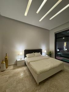 1 dormitorio con 1 cama grande, 2 mesas y 2 lámparas en لاڤانا en Unayzah