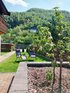 a patio with two chairs and a tree in the yard at Otnes Fjordside in Aurland