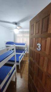 a room with three bunk beds and a wooden door at Hostel Lumaria 2 in Blumenau
