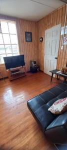 a living room with a black couch and a piano at Hostal Trautmann in Puerto Montt