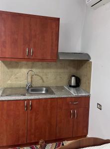 una cocina con armarios de madera y fregadero en Tourists Guest House, en Gjirokastra