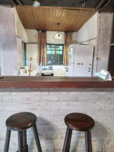 2 taburetes frente a una cocina con nevera en Casa en Costa Azul - Canelones, en La Floresta