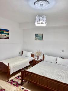 1 dormitorio con 2 camas y lámpara de araña en Tourists Guest House, en Gjirokastra