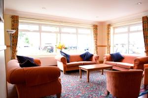 a living room with couches and a table and windows at The Riviera Hotel & Apartments - Alum Chine in Bournemouth