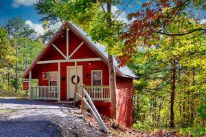 a small red house in the middle of a forest at Mountain Love Nest in Gatlinburg
