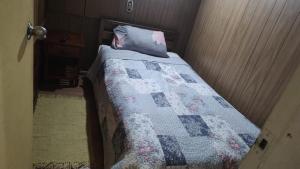 a bed with a quilt on it in a room at Hostal Trautmann in Puerto Montt