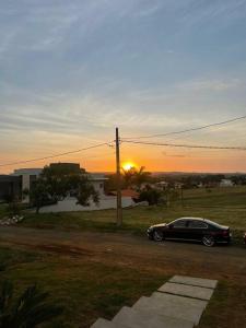un'auto parcheggiata in un parcheggio con il tramonto sullo sfondo di Casa de campo 1h30 de SP Ninho verde 1 a Porangaba