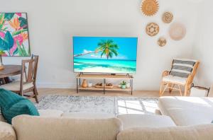 a living room with a flat screen tv on a wall at Stunning! Barefoot Breeze - Sale! New Waterfront Listing! Brand New Pool with Putting Green! in Bonita Springs