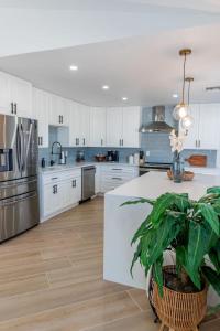 a kitchen with white cabinets and a table with a plant at Stunning! Barefoot Breeze - Sale! New Waterfront Listing! Brand New Pool with Putting Green! in Bonita Springs