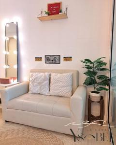 a white couch in a living room with a clock on the wall at La Casa Ysabela - Azure Affordable Staycation, Paranaque Metro Manila in Manila