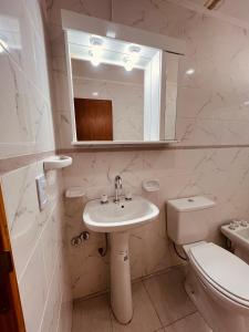 a bathroom with a sink and a toilet and a mirror at Departamento Rincón Patagónico in Esquel