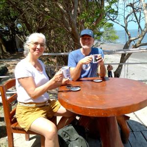 Altagracia的住宿－Beach cabin ometepe，坐在桌边喝咖啡的男人和女人