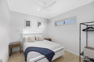 - une chambre blanche avec un lit et une fenêtre dans l'établissement The Hamptons Lakehouse, à Mannering Park