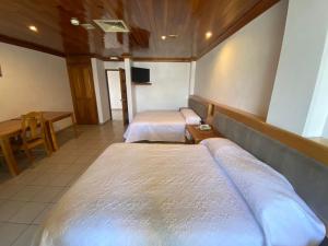 um quarto com duas camas e uma mesa e uma televisão em GARDEN SUITES em Aguascalientes