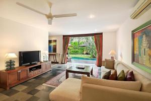 a living room with a couch and a tv at Sujiwana 2BR Luxury Jungle Pool View Villa CYN in Jimbaran
