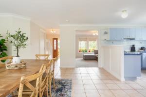 カトゥーンバにあるStunning Katoomba Home with Lush Garden&Playgroundの木製のテーブルと椅子のあるキッチンとリビングルーム