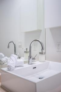 a bathroom sink with two faucets and towels at RivetStays - The Neptune in Toronto