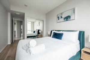 a bedroom with a large white bed with towels on it at RivetStays - The Neptune in Toronto