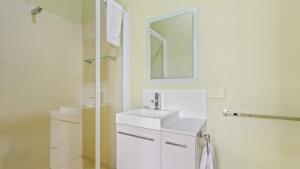 a white bathroom with a sink and a mirror at The Hide Away - Scenic Waterfront Escape in Kalimna +25 photos