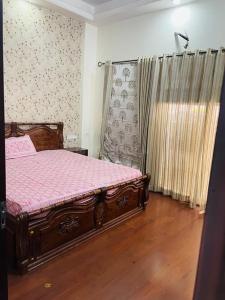 sypialnia z drewnianym łóżkiem z różową pościelą i oknem w obiekcie Naini House w mieście Nainital
