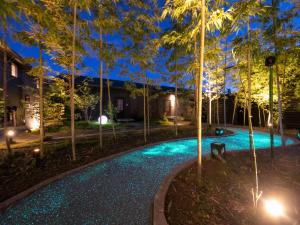 - une piscine avec des arbres et des lumières la nuit dans l'établissement 湯本庵清姫, à Kirishima