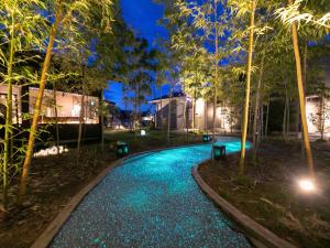 uma piscina à noite com árvores e luzes em 湯本庵清姫 em Kirishima