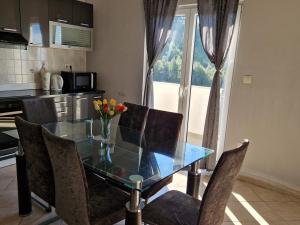 een keuken met een glazen tafel met stoelen en een raam bij Apartments with a parking space Podstrana, Split - 22374 in Podstrana