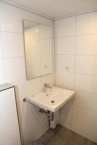 a white bathroom with a sink and a mirror at Uttumer Mühle Daike in Uttum