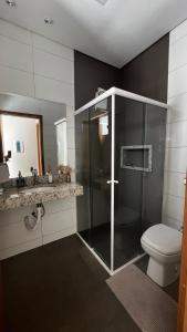 a bathroom with a glass shower and a toilet at Casa com Piscina em Maringá in Maringá